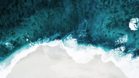 Aerial view of ocean waves meeting a sandy shoreline